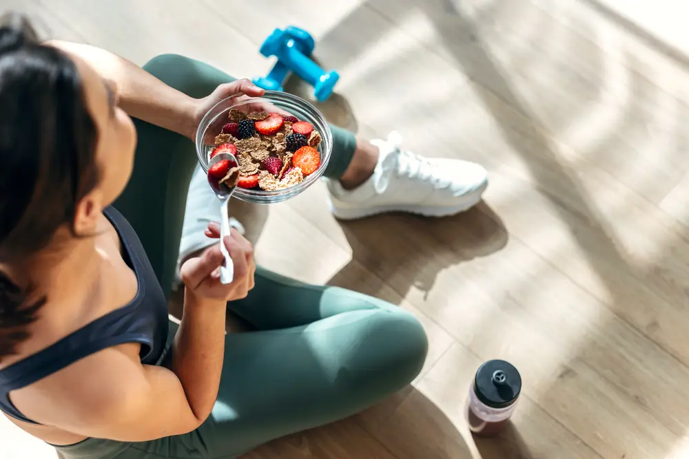 Persona comiendo un bowl de frutas después de entrenar